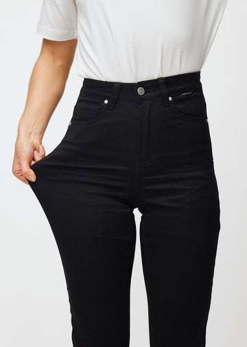 Model strækker jeansene ved låret for at vise stretch.