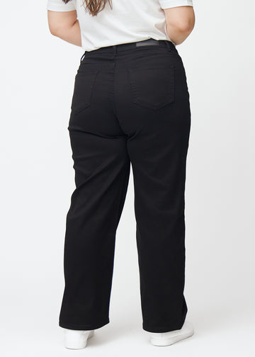 Sorte højtaljede jeans, som sidder til i taljen og har en løs pasform med bredde ned, set bagfra på en plus-size model så man kan se hele produktet.