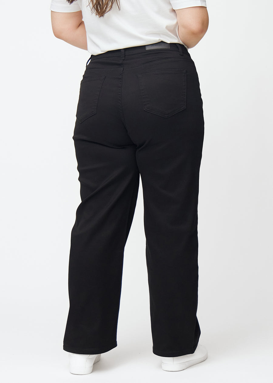 Sorte højtaljede jeans, som sidder til i taljen og har en løs pasform med bredde ned, set bagfra på en plus-size model så man kan se hele produktet.