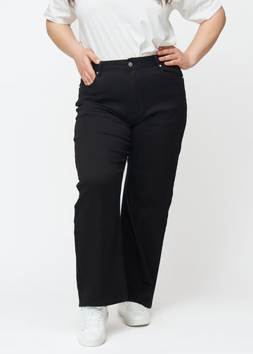 Sorte højtaljede jeans af modellen Ravens, som sidder til i taljen og har en løs pasform med bredde ned, på en plus-size model set forfra.