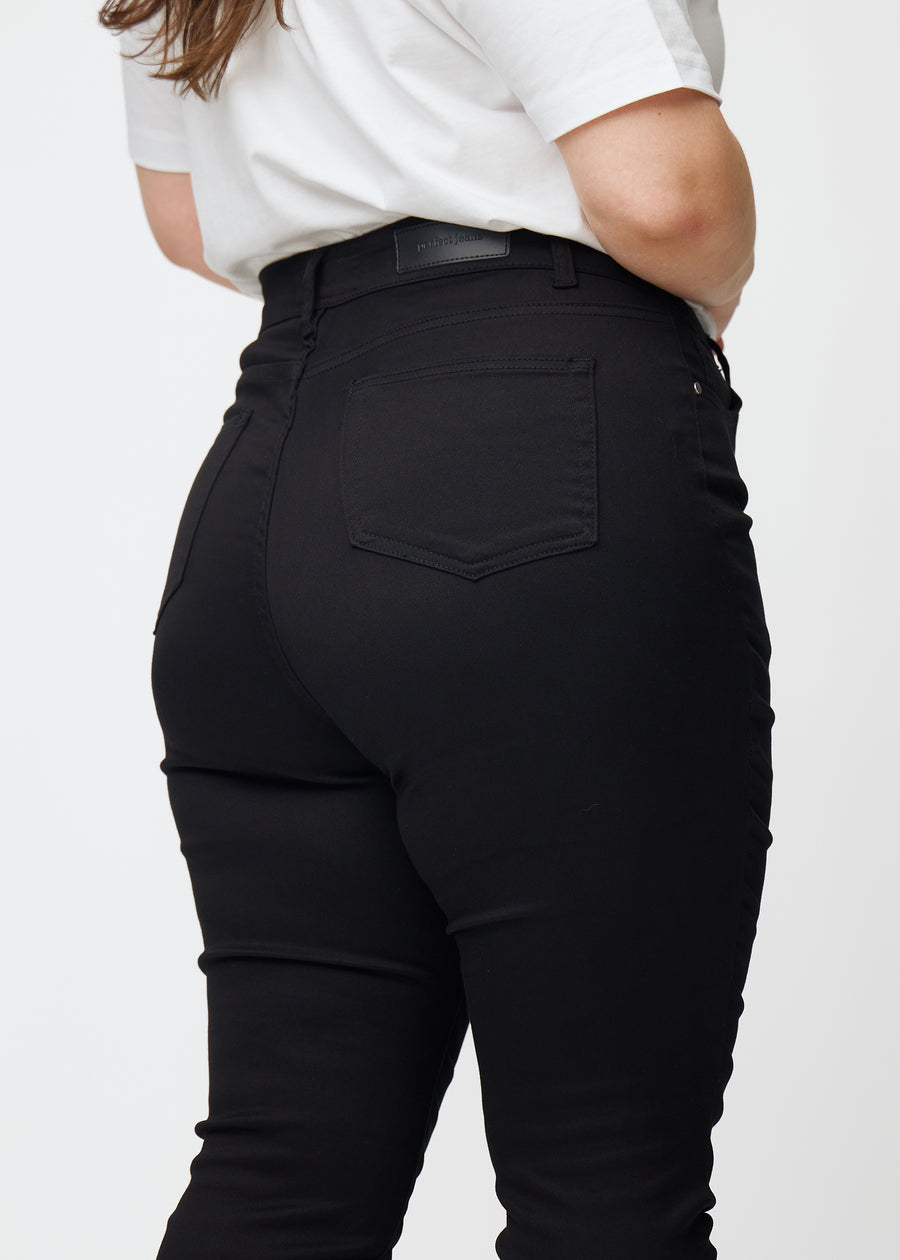Billedet viser et nærbillede af sorte plus size high rise jeans til kvinder i farven Ravens i skinny fit set bagfra.