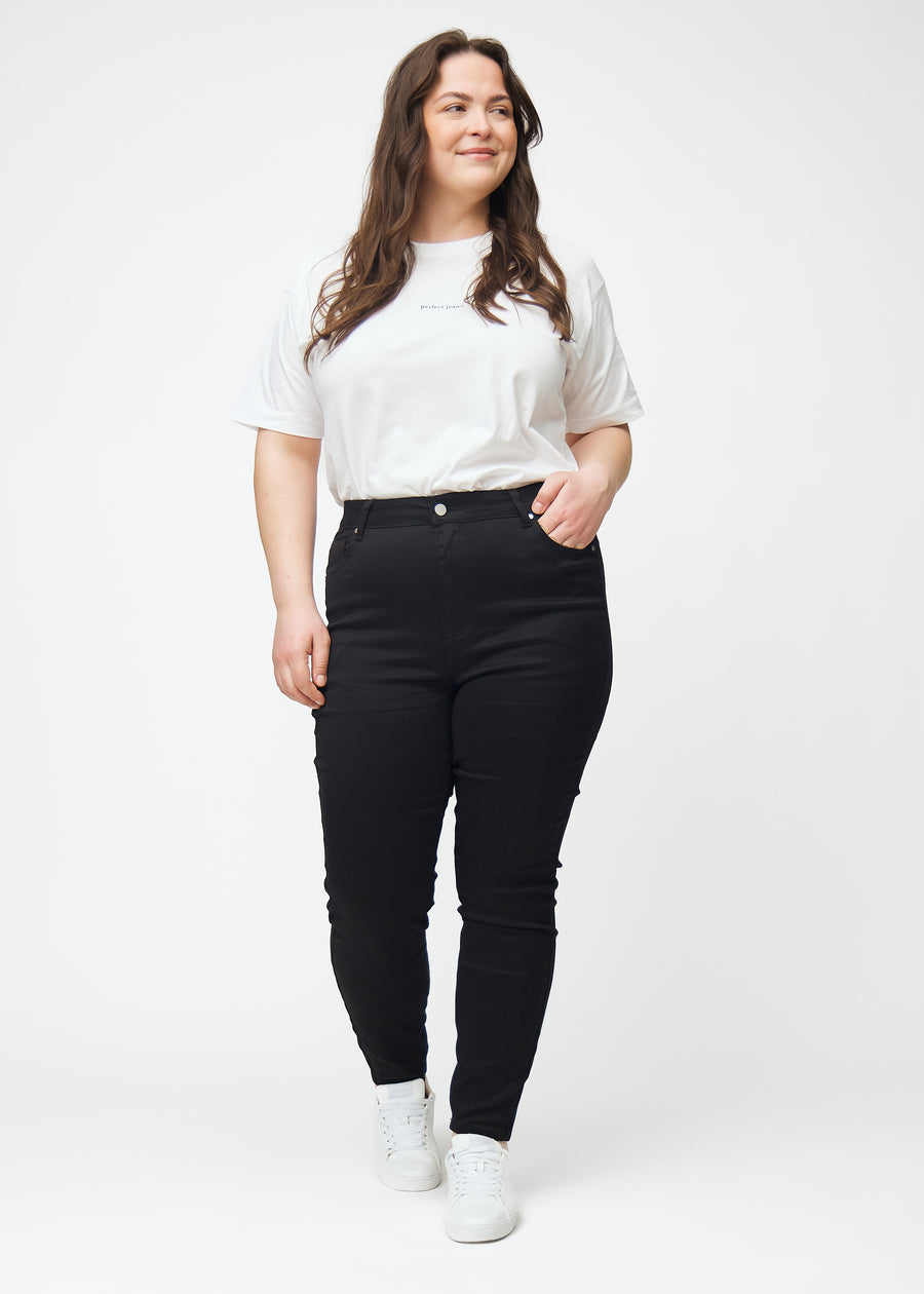 Dette er et fuldt billede af en plus size model iført sorte high rise skinny jeans til kvinder i farven Ravens.