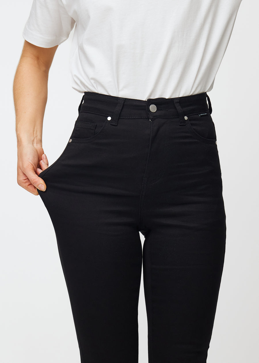 En model strækker de sorte Ravens stretch jeans med høj talje for at illustrere pasformen.