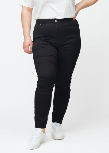 En plus size model fremviser sorte high rise skinny jeans til kvinder i farven Ravens set forfra.