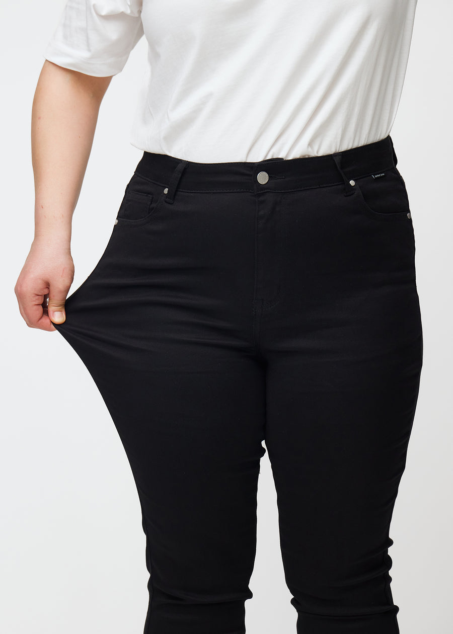 En plus size model strækker de sorte stretch jeans med høj talje i farven Ravens.