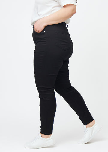 Sorte plus size high rise skinny jeans til kvinder i farven Ravens ses fra siden på en model.