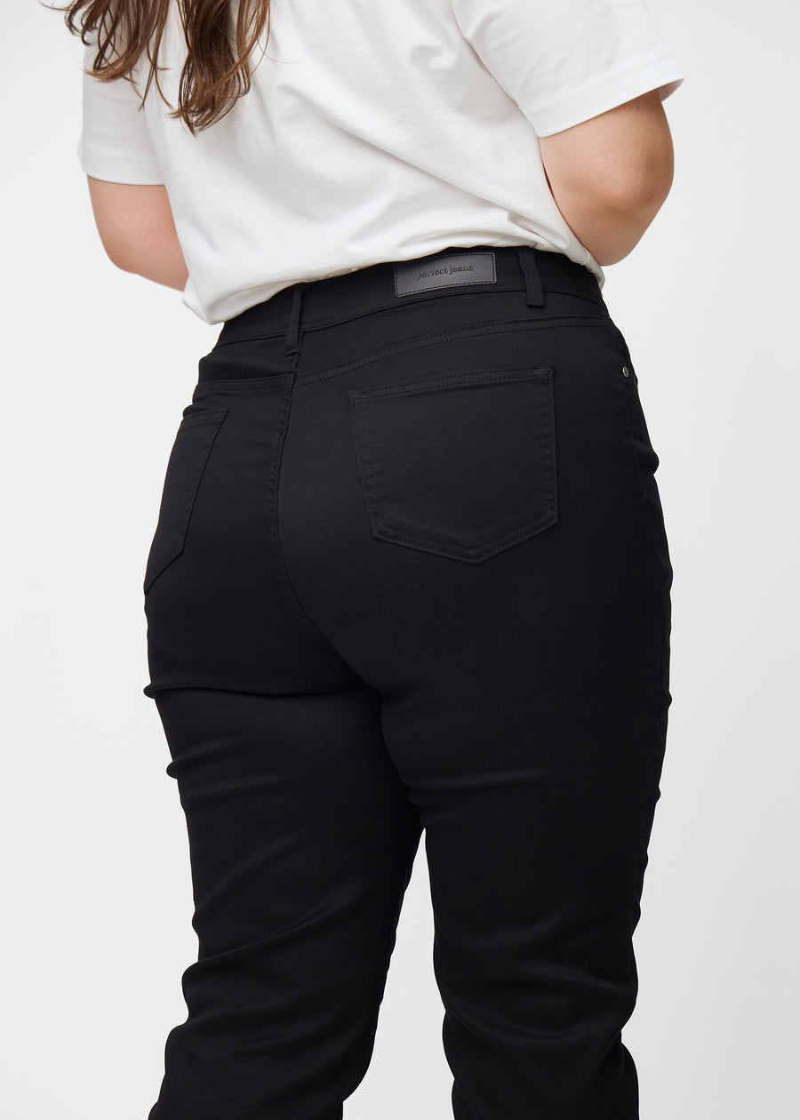 Sorte højtaljede slim jeans set bagfra tæt på en plus-size model for at vise detaljer.