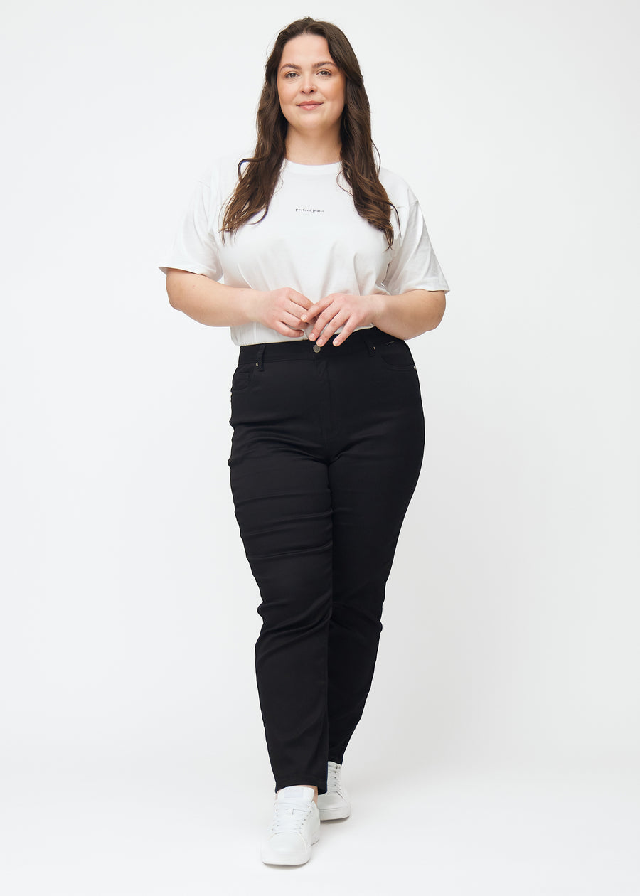 Fuldt billede af en plus-size model i sorte højtaljede slim jeans.
