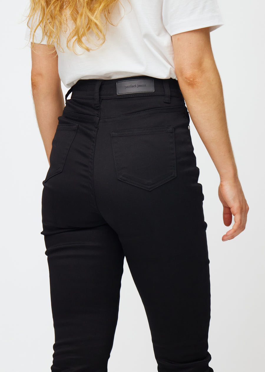 Sorte højtaljede slim jeans set bagfra tæt på for at vise detaljer.