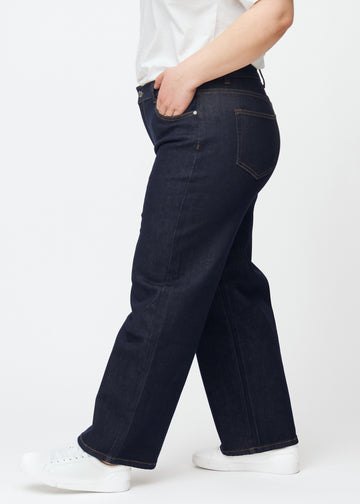 Dyb mørkeblå denim jeans til kvinder i farven Midnights med loose pasform set fra siden på plus-size model.
