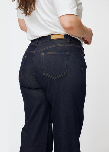 Dyb mørkeblå denim jeans til kvinder i farven Midnights set bagfra tæt på på plus-size model.