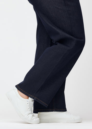 Dyb mørkeblå denim jeans til kvinder i farven Midnights med loose pasform set tæt på ved anklerne på plus-size model for at vise den brede afslutning.