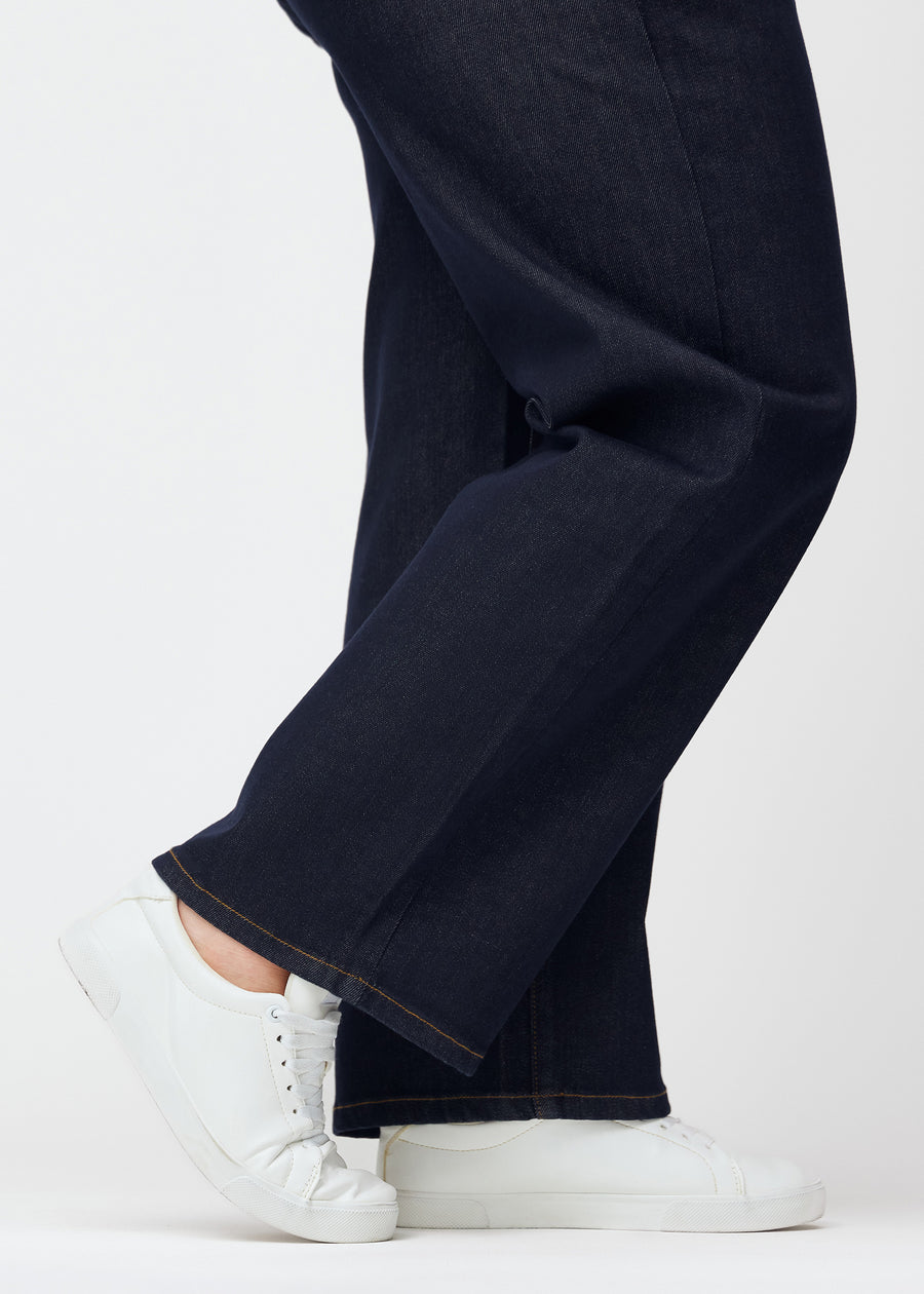 Dyb mørkeblå denim jeans til kvinder i farven Midnights med loose pasform set tæt på ved anklerne på plus-size model for at vise den brede afslutning.