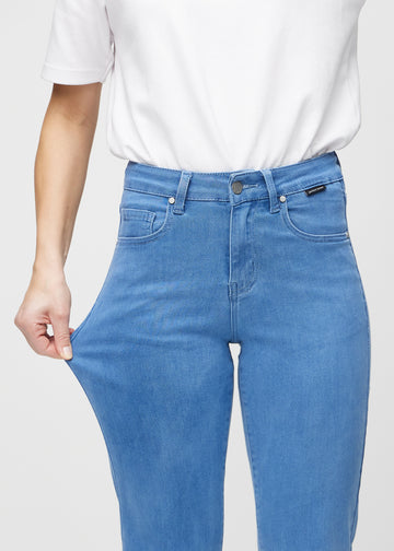 Model strækker jeansene ved låret for at vise stretch.