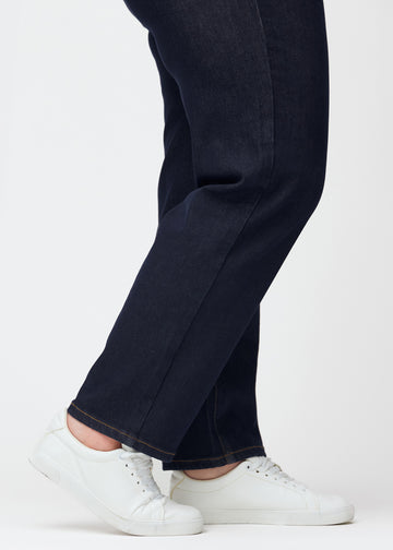 Dyb mørkeblå denim jeans til kvinder i farven Midnights med regular pasform set tæt på ved anklerne på plus-size model for at vise den lige afslutning.