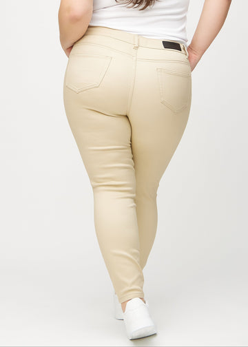Beige skinny jeans set bagfra på en plus-size model, så man kan se hele produktet.