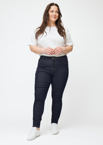 Fuldt billede af plus-size model i dyb mørkeblå denim jeans til kvinder i farven Midnights med skinny pasform.
