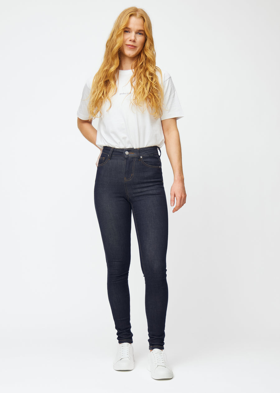 Fuldt billede af model i dyb mørkeblå denim jeans til kvinder i farven Midnights med skinny pasform.
