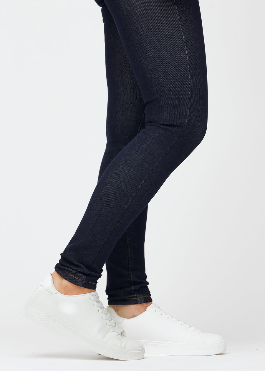 Dyb mørkeblå denim jeans til kvinder i farven Midnights med skinny pasform set tæt på ved anklerne for at vise den tætsiddende afslutning.