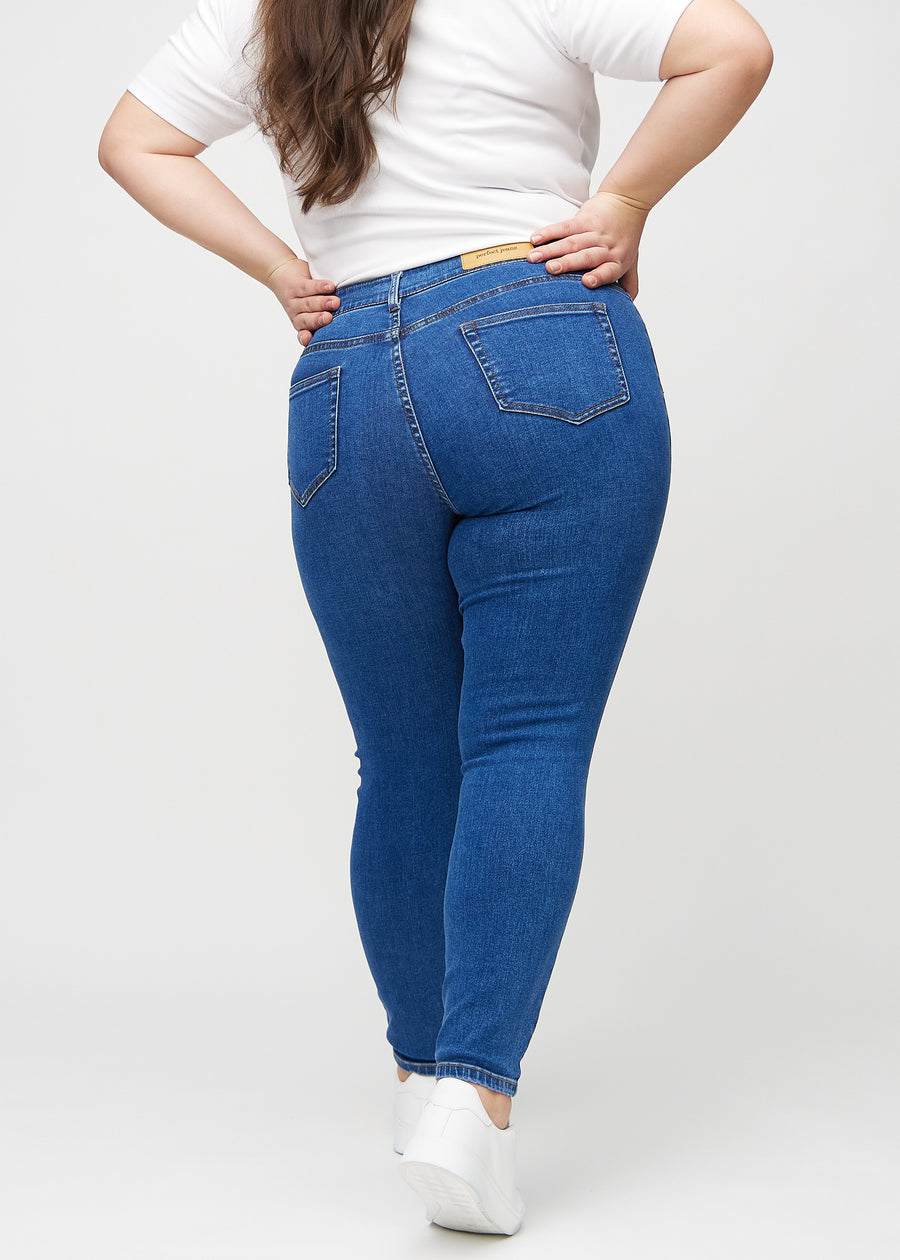 Mørk denim skinny jeans set bagfra på en plus-size model, så man kan se hele produktet.&