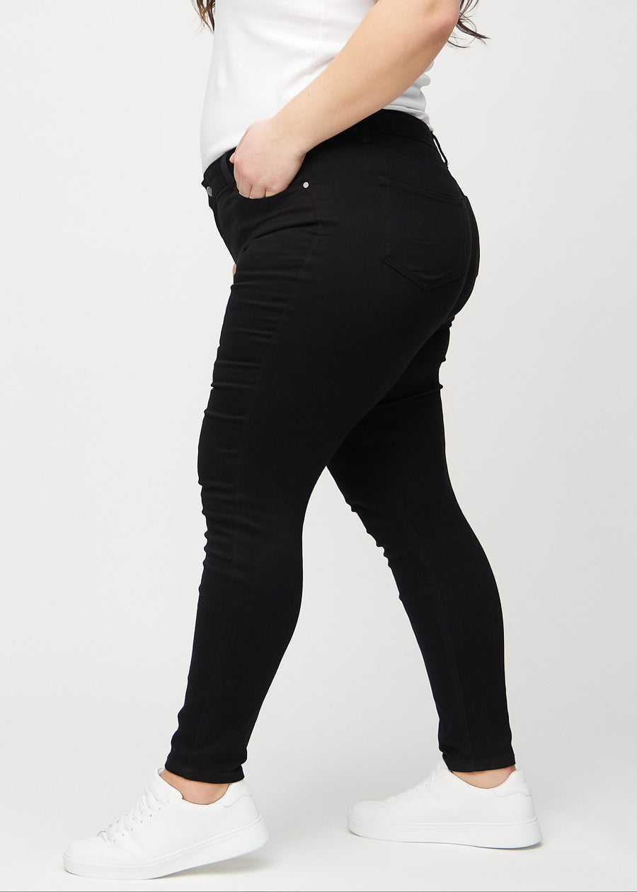 Sorte skinny jeans set fra siden på en plus-size model.