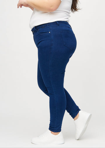 Mørkeblå skinny jeans set fra siden på en plus-size model.