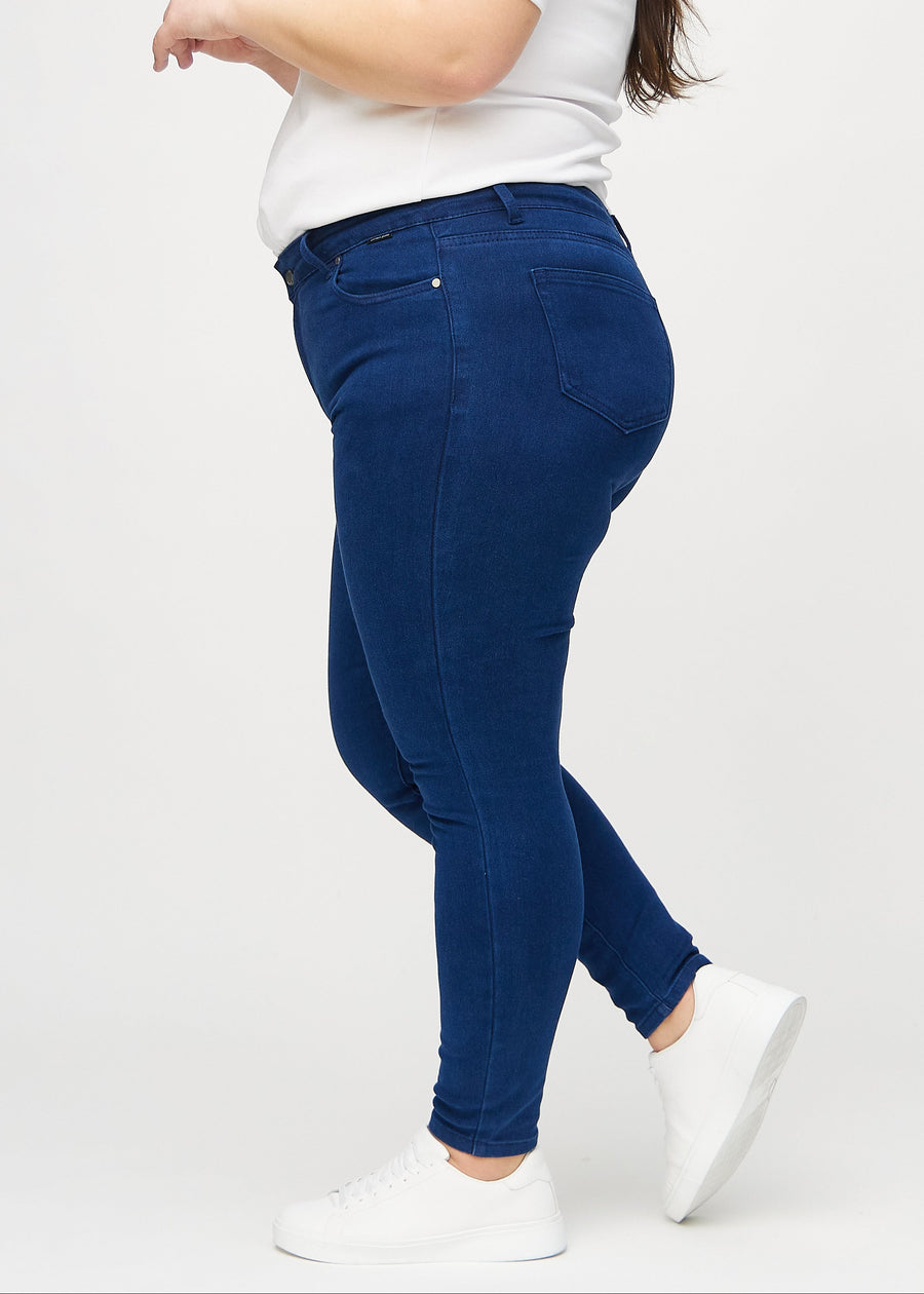 Mørkeblå skinny jeans set fra siden på en plus-size model.
