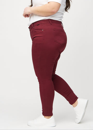Mørkerøde skinny jeans set fra siden på en plus-size model.