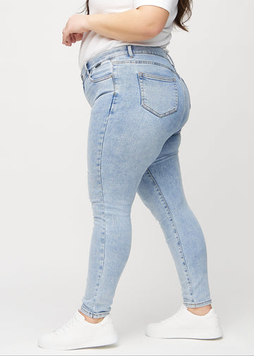 Lys denim skinny jeans set fra siden på en plus-size model.
