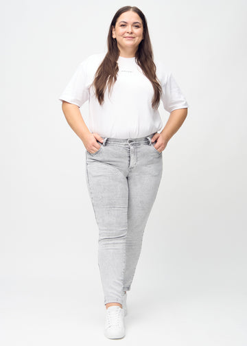 Fuldt billede af en plus-size model i lysegrå denim slim jeans.