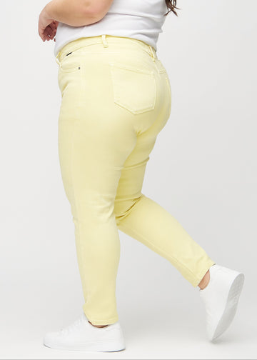 Lysegule slim jeans set fra siden på en plus-size model.