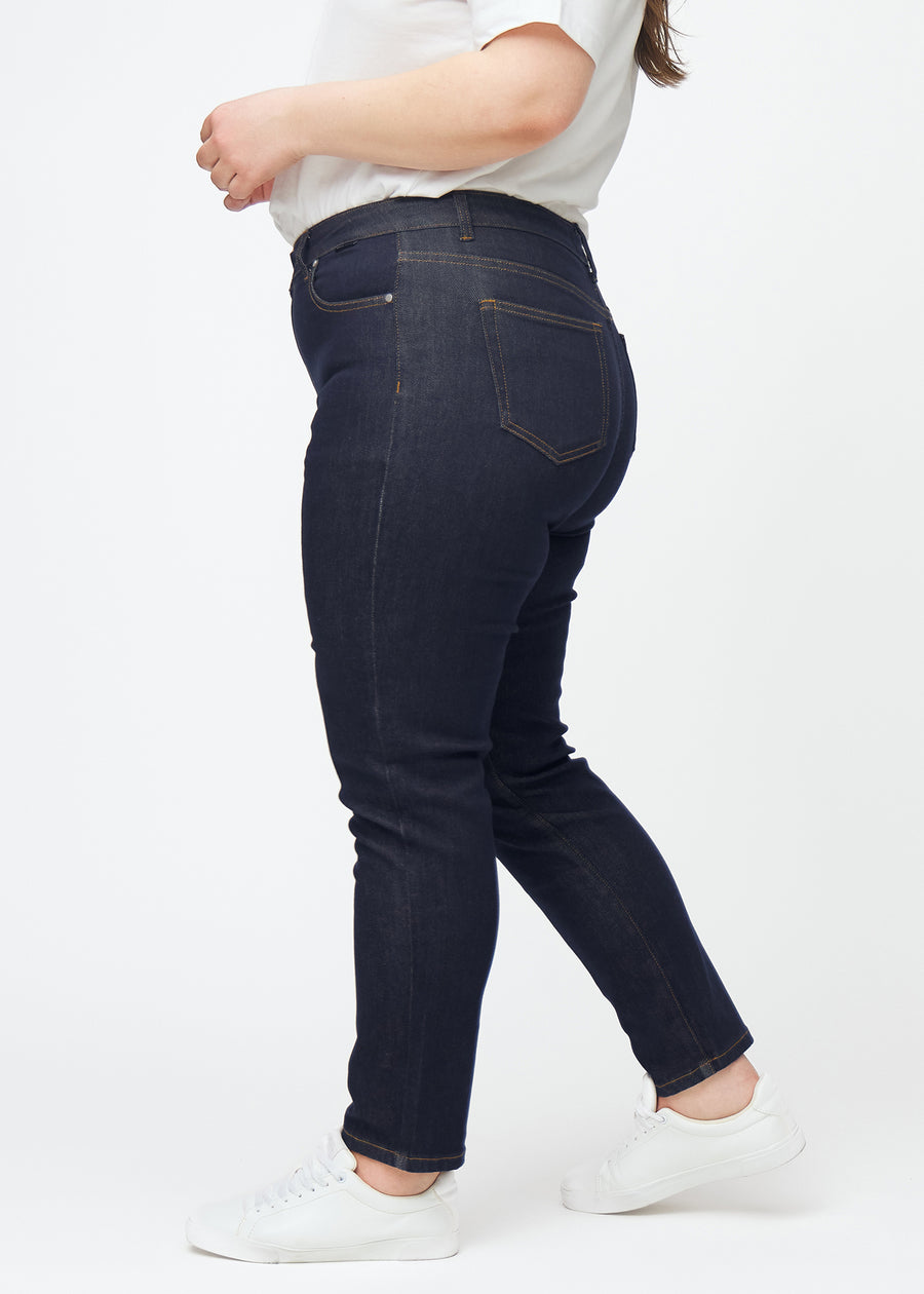 Dyb mørkeblå denim jeans til kvinder i farven Midnights med slim pasform set fra siden på plus-size model.