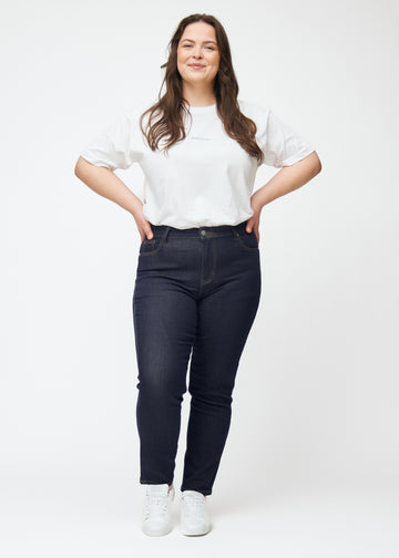 Fuldt billede af plus-size model i dyb mørkeblå denim jeans til kvinder i farven Midnights med slim pasform.
