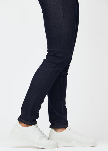 Dyb mørkeblå denim jeans til kvinder i farven Midnights med slim pasform set tæt på ved anklerne for at vise den figursyede afslutning.