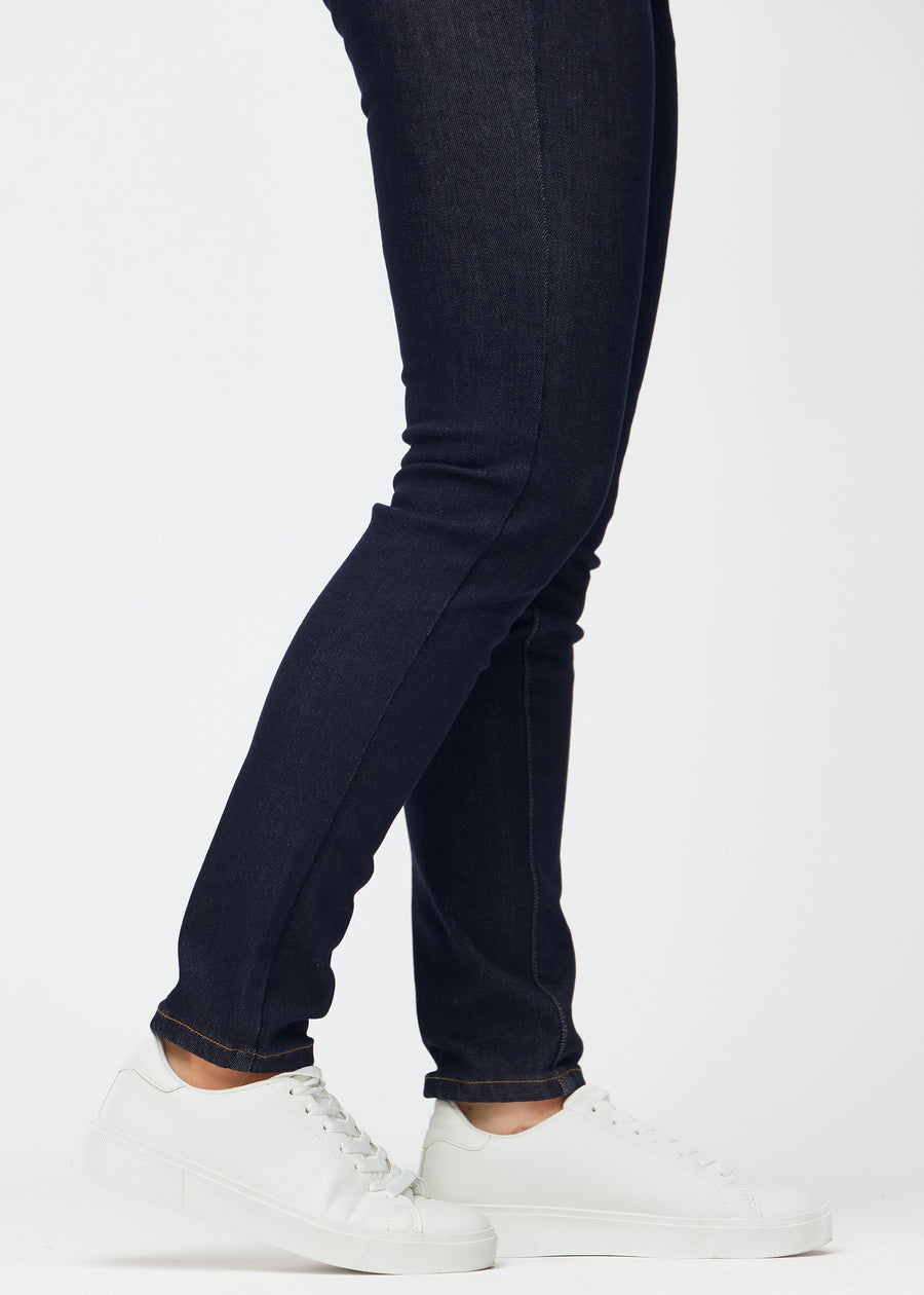 Dyb mørkeblå denim jeans til kvinder i farven Midnights med slim pasform set tæt på ved anklerne for at vise den figursyede afslutning.