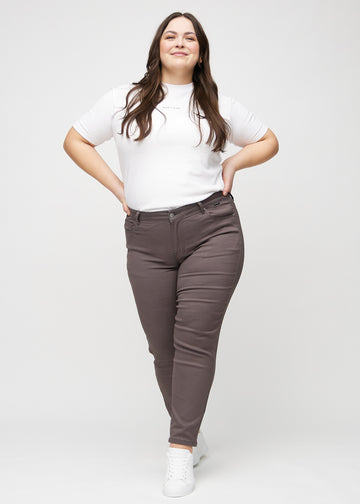 Fuldt billede af en plus-size model i gråbrune slim jeans.