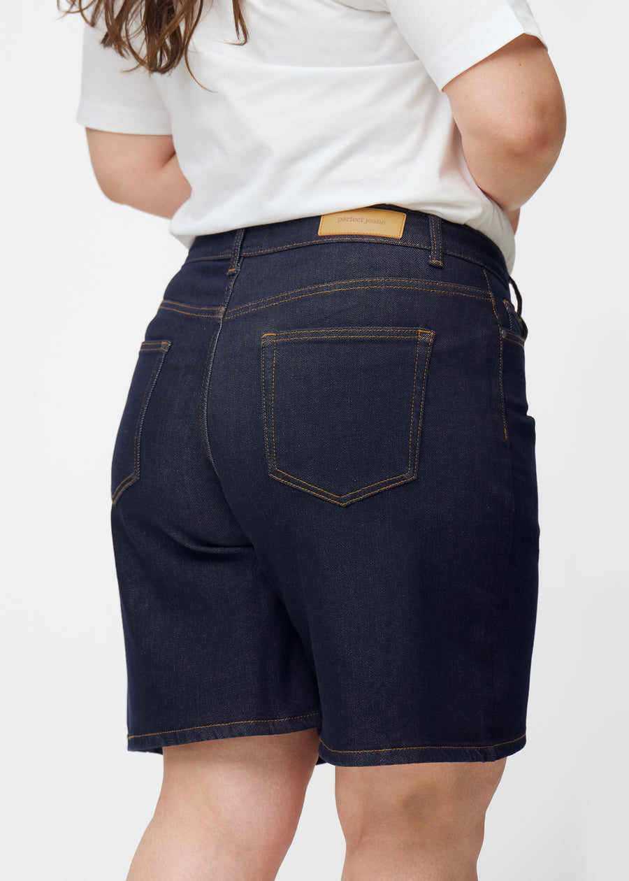 Dyb mørkeblå denim shorts til kvinder i farven Midnights set bagfra tæt på på plus-size model.