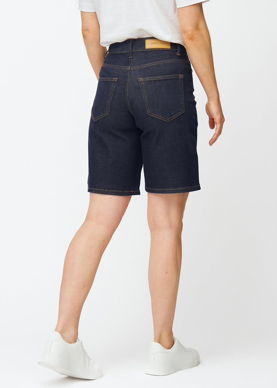 Dyb mørkeblå denim shorts til kvinder i farven Midnights set bagfra, så længden til lige over knæet kan ses.