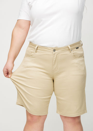 Plus-size model strækker shortsene ved låret for at vise stretch.