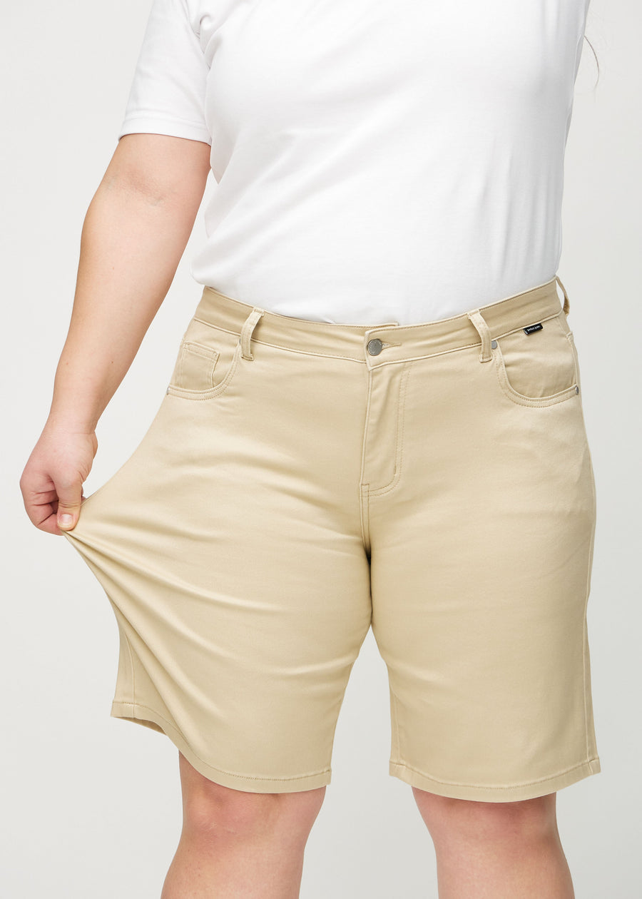 Plus-size model strækker shortsene ved låret for at vise stretch.