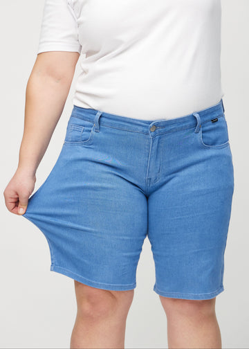Plus-size model strækker shortsene ved låret for at vise stretch.