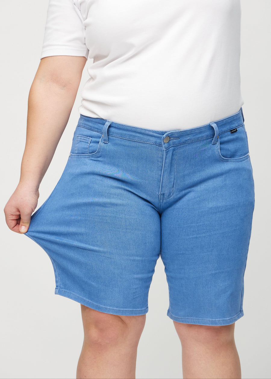 Plus-size model strækker shortsene ved låret for at vise stretch.