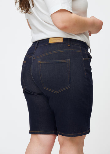 Dyb mørkeblå denim shorts til kvinder i farven Midnights set bagfra tæt på på plus-size model.