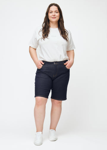 Fuldt billede af plus-size model i dyb mørkeblå denim shorts til kvinder i farven Midnights med regular pasform.