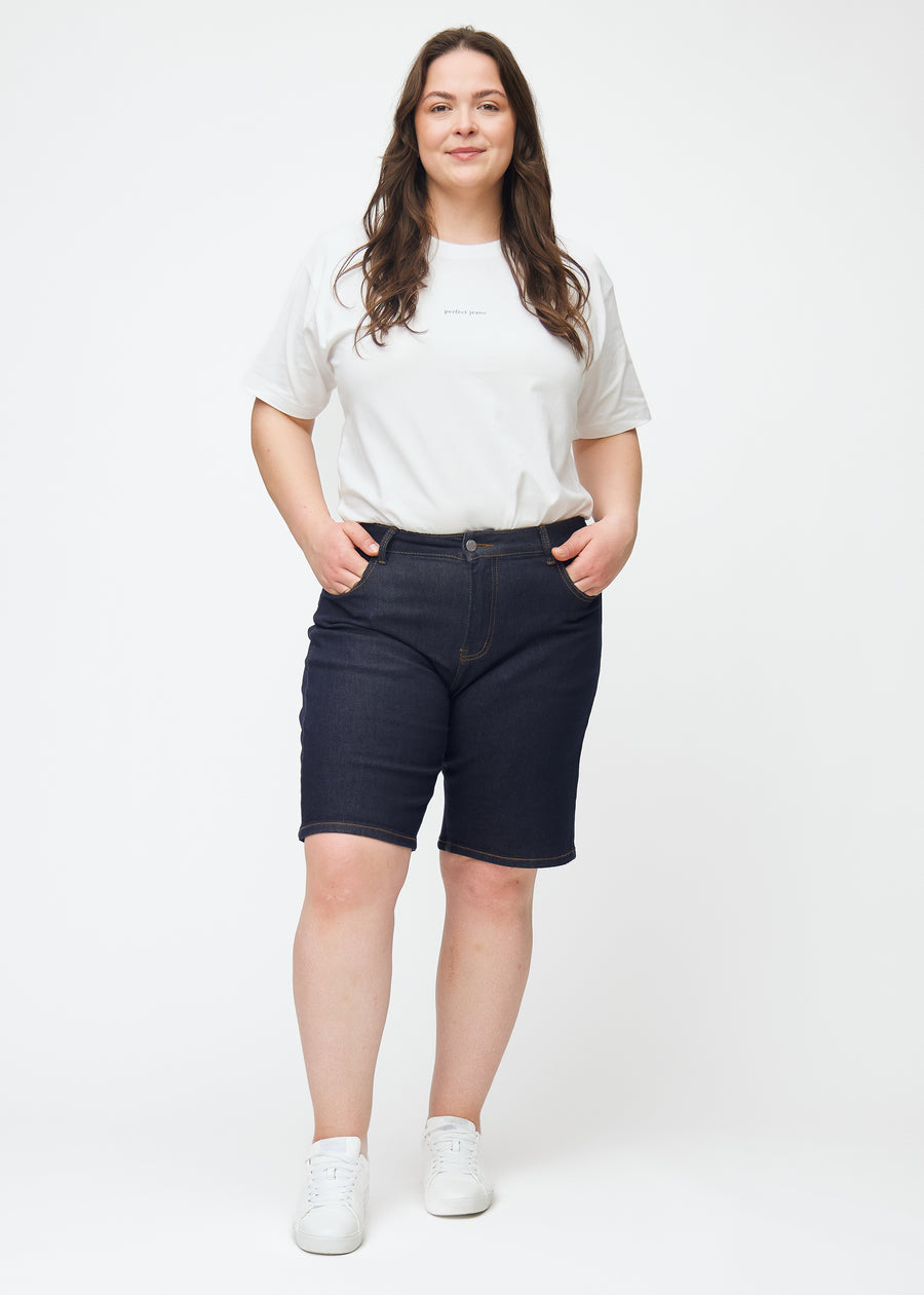 Fuldt billede af plus-size model i dyb mørkeblå denim shorts til kvinder i farven Midnights med regular pasform.