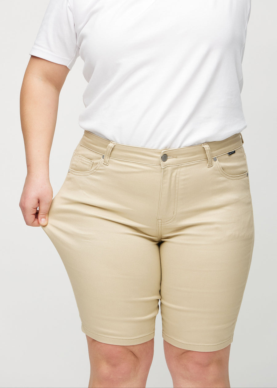 Plus-size model strækker shortsene ved låret for at vise stretch.