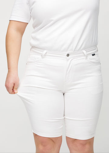 Plus-size model strækker shortsene ved låret for at vise stretch.