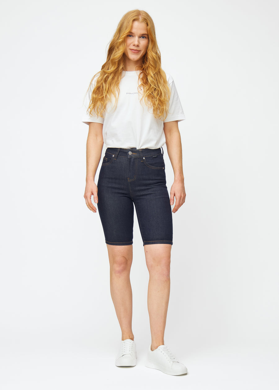 Fuldt billede af model i dyb mørkeblå denim shorts til kvinder i farven Midnights med skinny pasform.