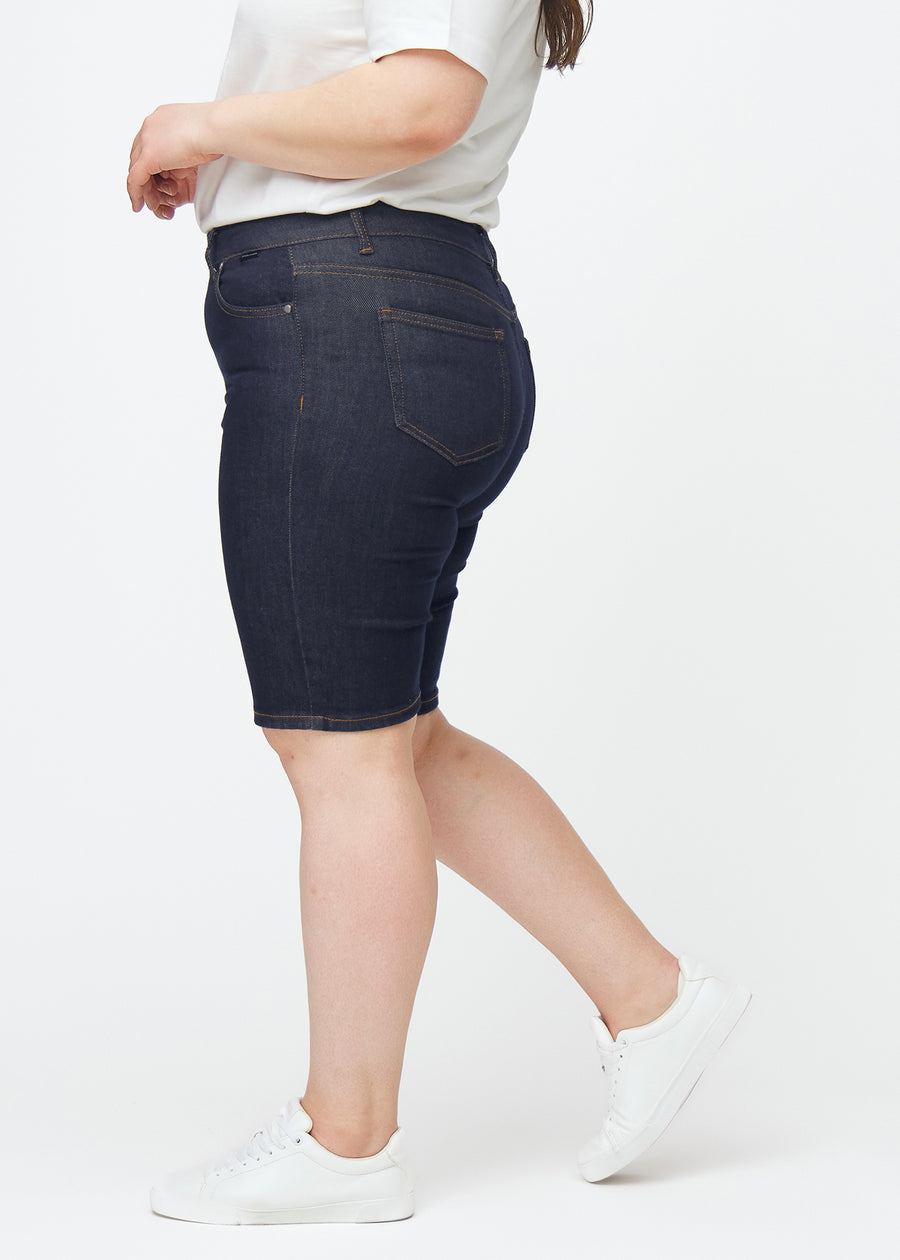 Dyb mørkeblå denim shorts til kvinder i farven Midnights med skinny pasform set fra siden på plus-size model.