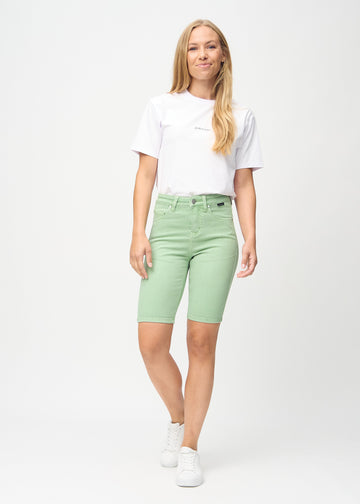 Fuldt billede af model i lysegrønne skinny middle shorts.